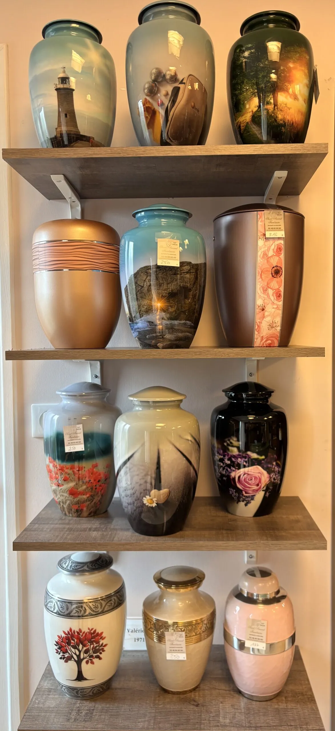 Sélection d'urnes cinéraires décorées exposées sur des étagères.