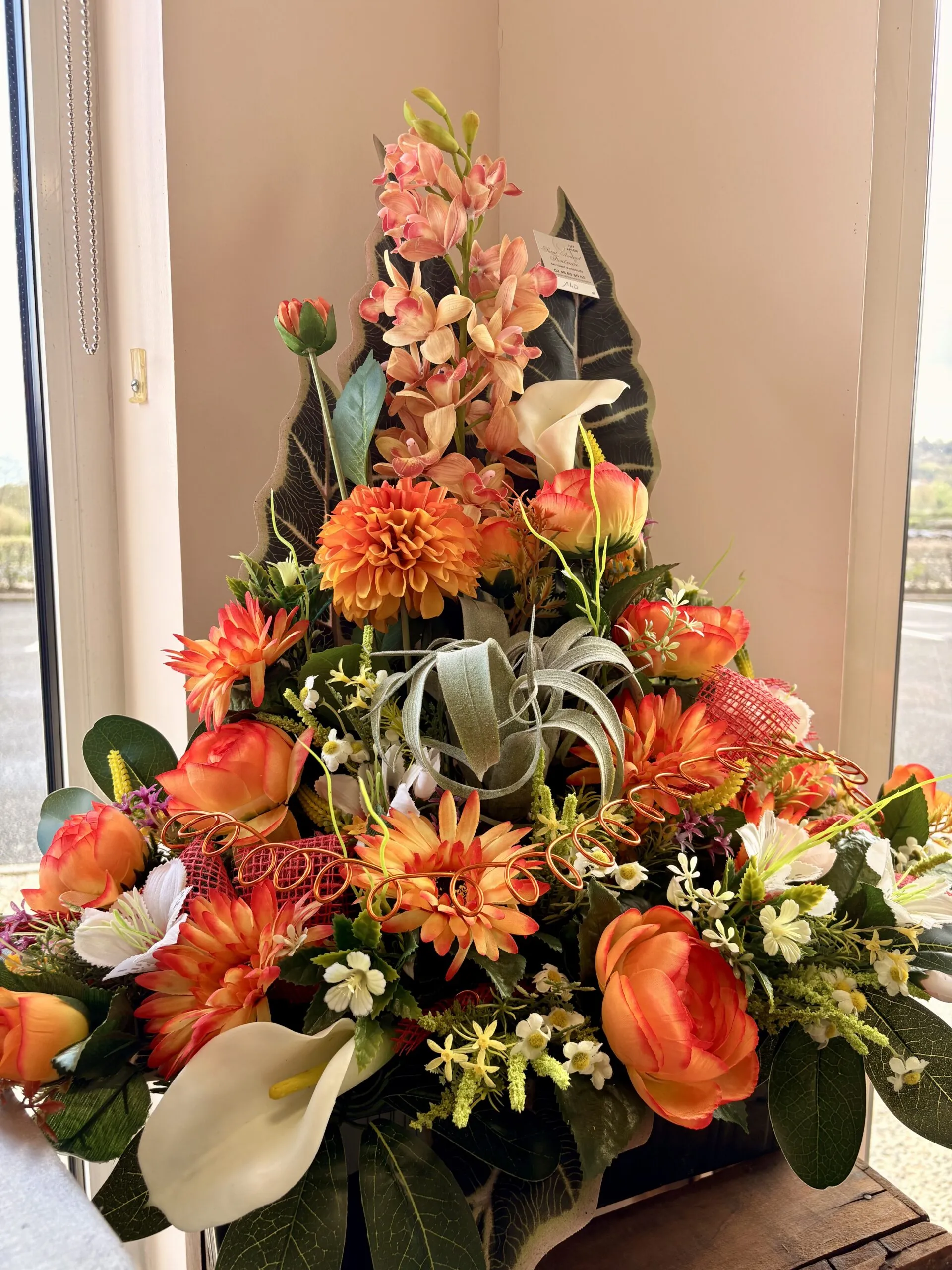 Composition de fleurs artificielles colorées pour hommage funéraire.