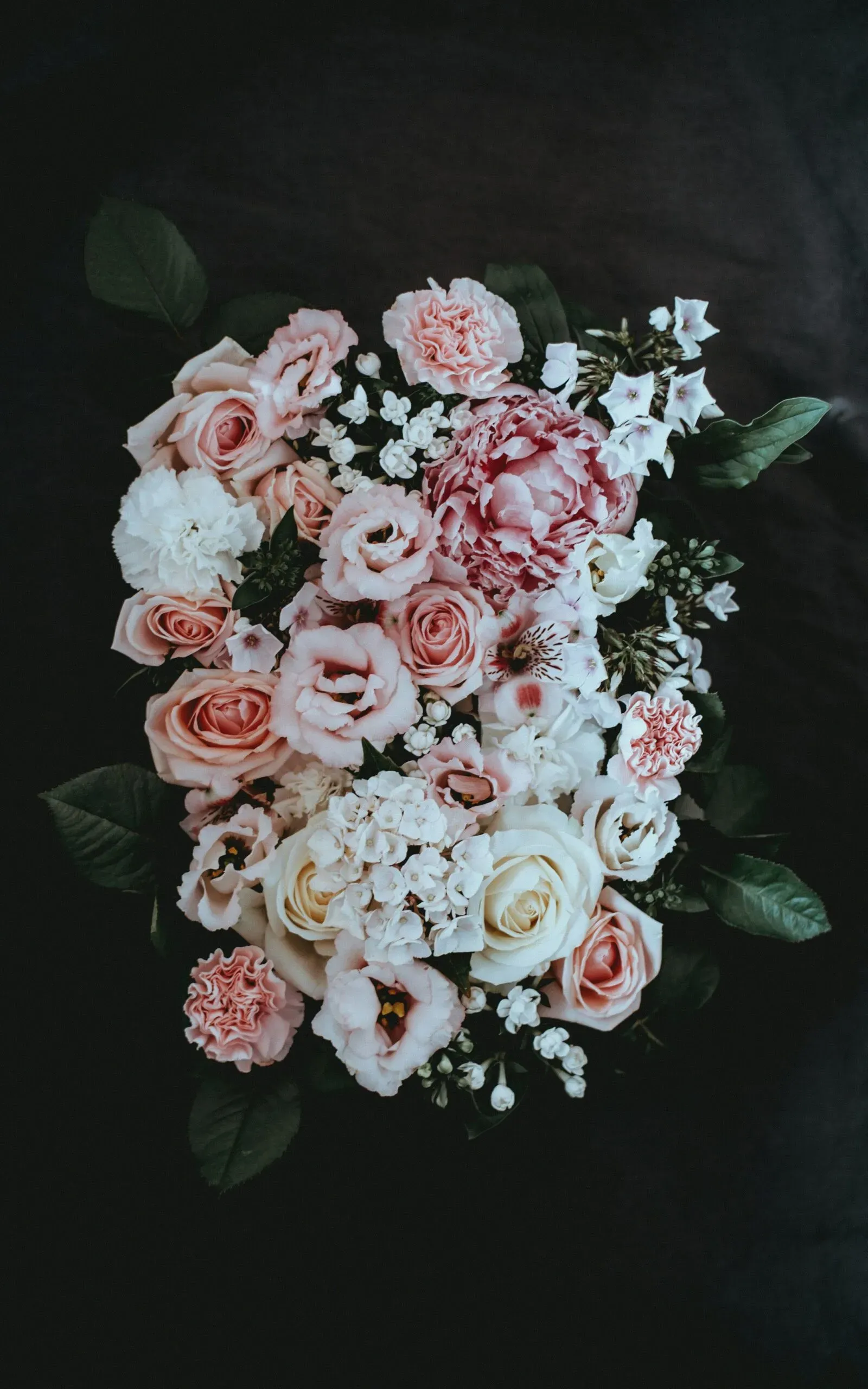 Composition florale élégante de pivoines, roses et œillets en hommage.