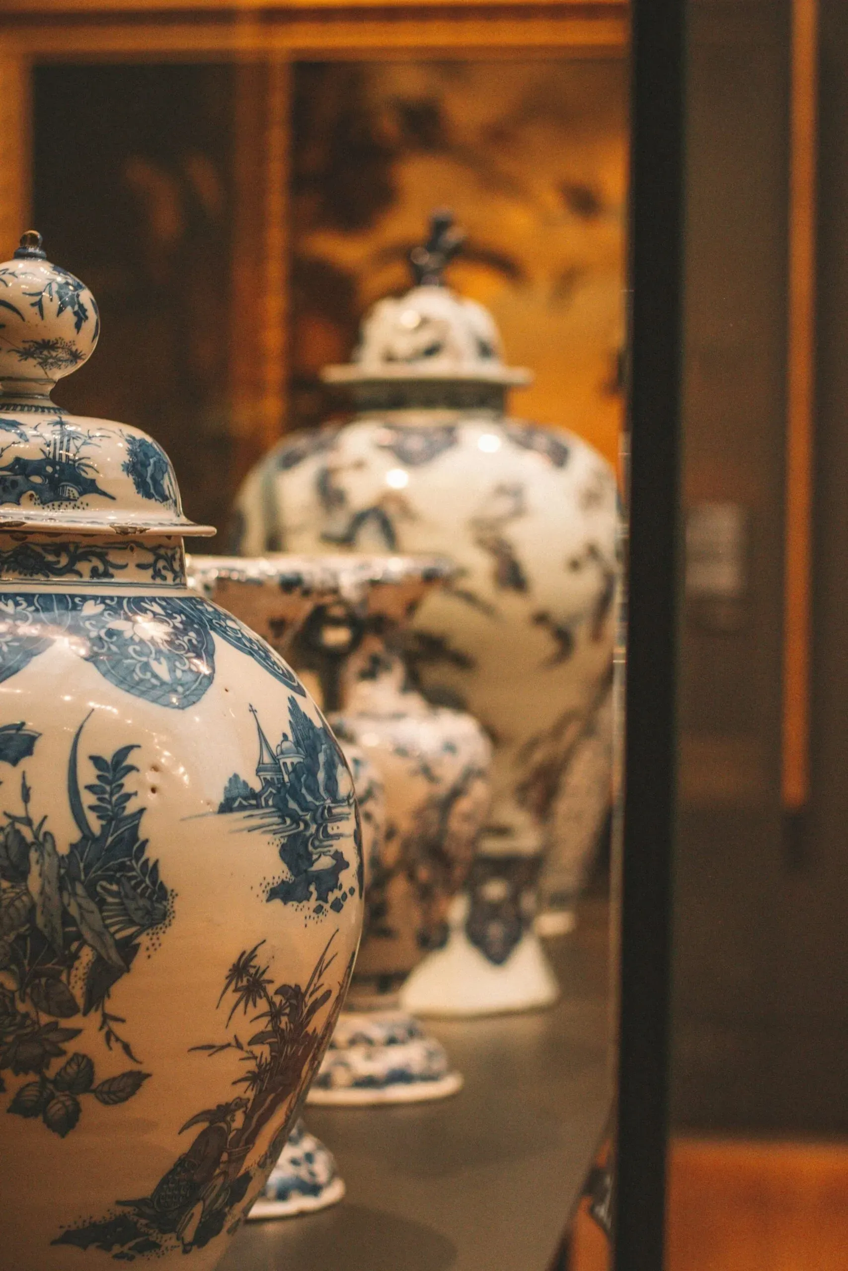 Urnes cinéraires en porcelaine décorée exposées en vitrine.