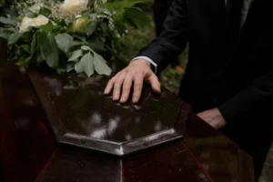Main posée délicatement sur un cercueil lors d'une cérémonie de funérailles.